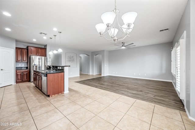16763 W Magnolia St, Goodyear, AZ 85338 - kitchen featuring arched walkways, a chandelier, dark countertops, a sink, and light tile patterned floors