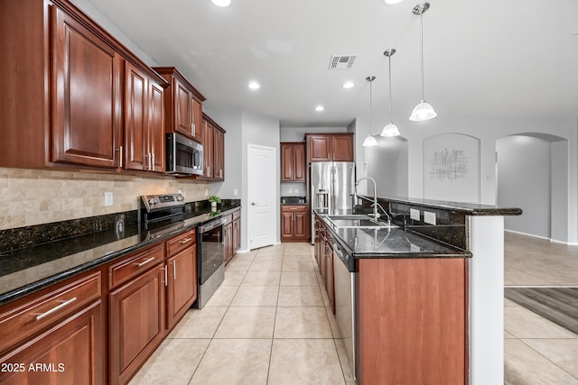 16763 W Magnolia St, Goodyear, AZ 85338 - kitchen featuring stainless steel appliances, arched walkways, a sink, decorative backsplash, and light tile patterned flooring