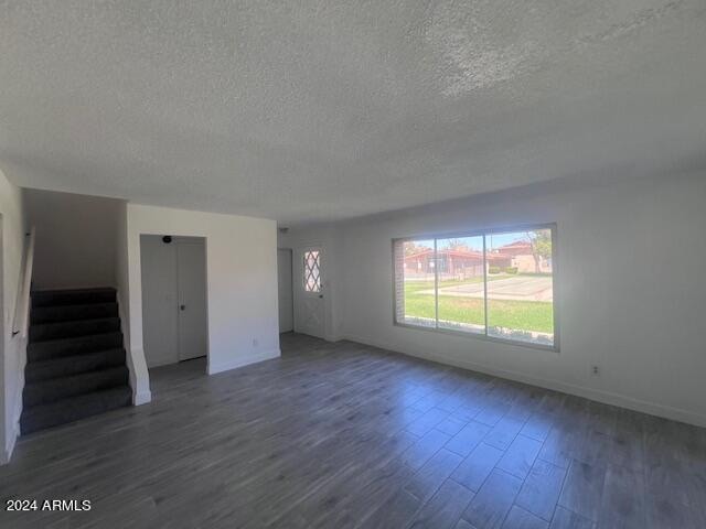 unfurnished living room with dark hardwood / wood-style flooring and a textured ceiling