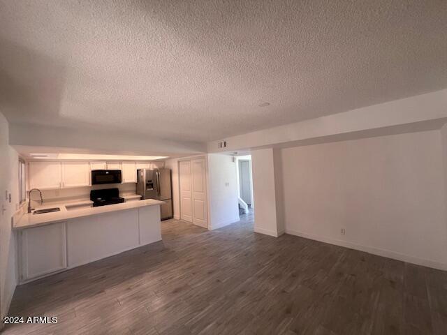 kitchen featuring dark hardwood / wood-style flooring, black appliances, kitchen peninsula, sink, and white cabinetry