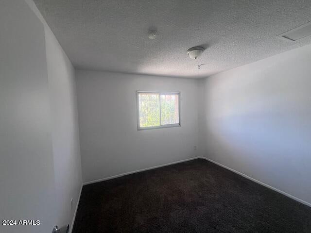 carpeted empty room featuring a textured ceiling