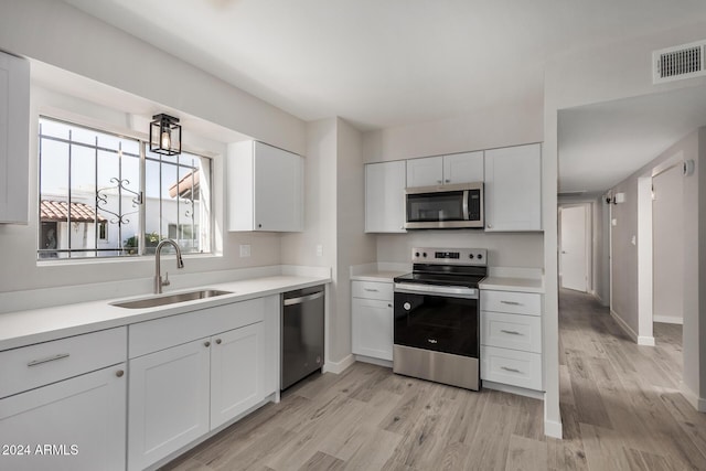 kitchen featuring white cabinetry, sink, light hardwood / wood-style flooring, and appliances with stainless steel finishes