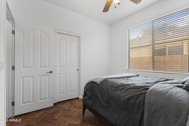 bedroom with dark parquet flooring, a closet, and ceiling fan