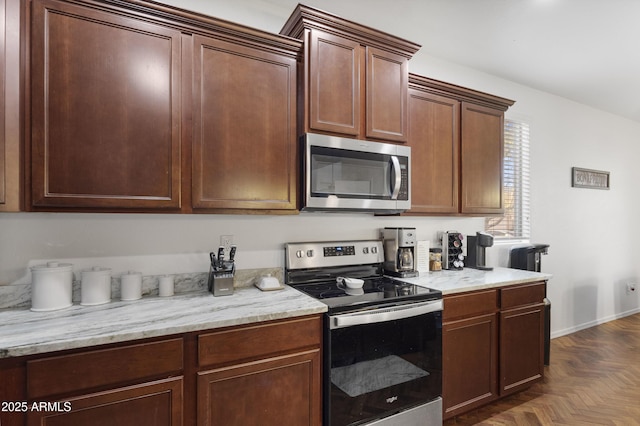 kitchen with dark parquet flooring, light stone counters, and stainless steel appliances