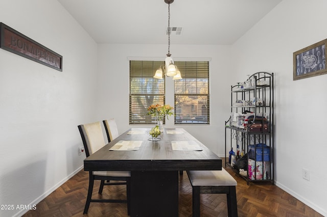 dining space featuring dark parquet flooring and an inviting chandelier