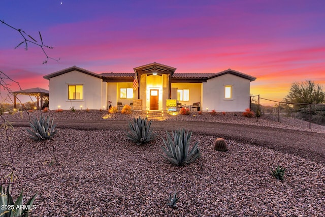 view of front of property with a tile roof, fence, and stucco siding