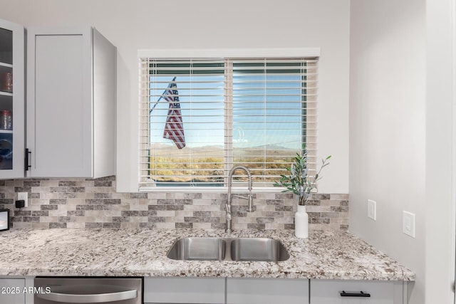 kitchen featuring stainless steel dishwasher, a sink, glass insert cabinets, and a healthy amount of sunlight