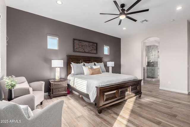 bedroom with arched walkways, light wood finished floors, recessed lighting, visible vents, and baseboards