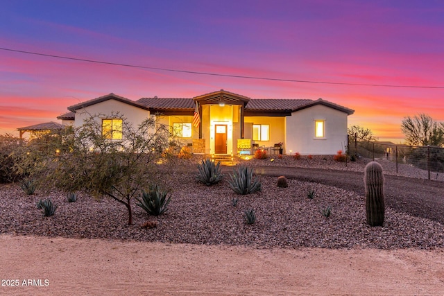 view of front of house featuring a tiled roof, fence, and stucco siding