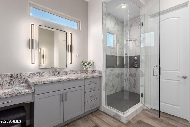 bathroom featuring a marble finish shower, wood finished floors, and vanity