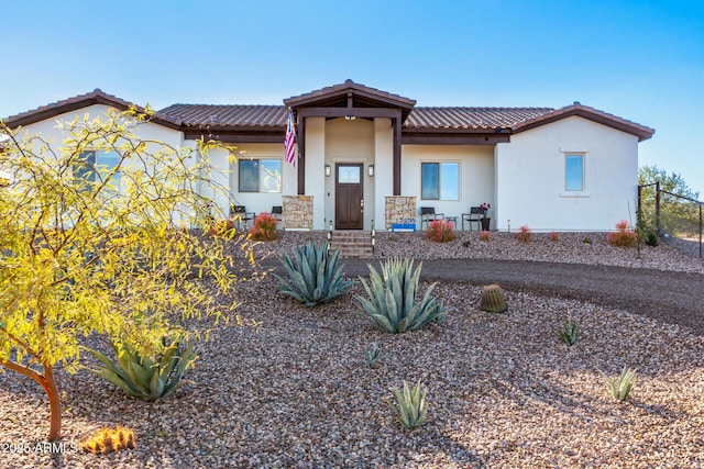 view of front of property featuring covered porch, fence, a tiled roof, and stucco siding