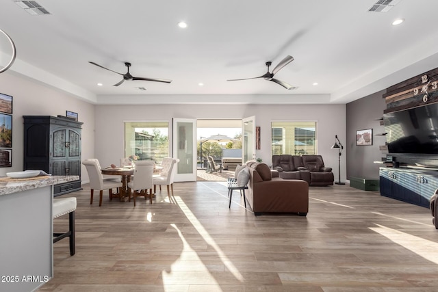 living room featuring ceiling fan, light wood-style flooring, and visible vents