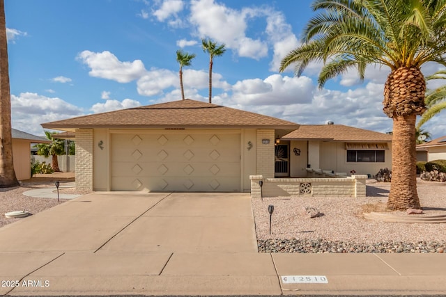 ranch-style home with a garage, driveway, brick siding, and roof with shingles