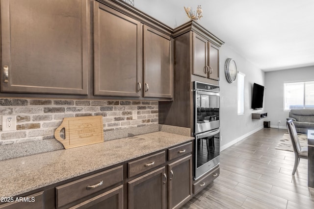 kitchen with backsplash, dark brown cabinets, open floor plan, and stainless steel double oven