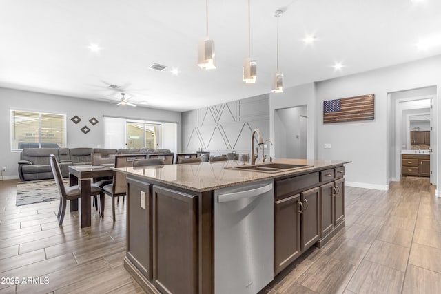 kitchen with stainless steel dishwasher, a sink, open floor plan, light stone countertops, and visible vents