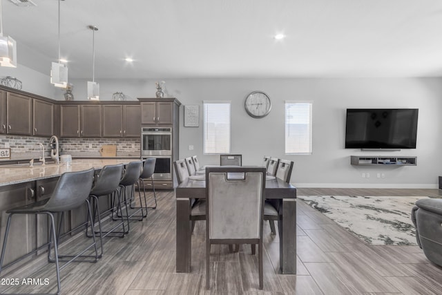 dining space featuring baseboards, wood finished floors, and recessed lighting