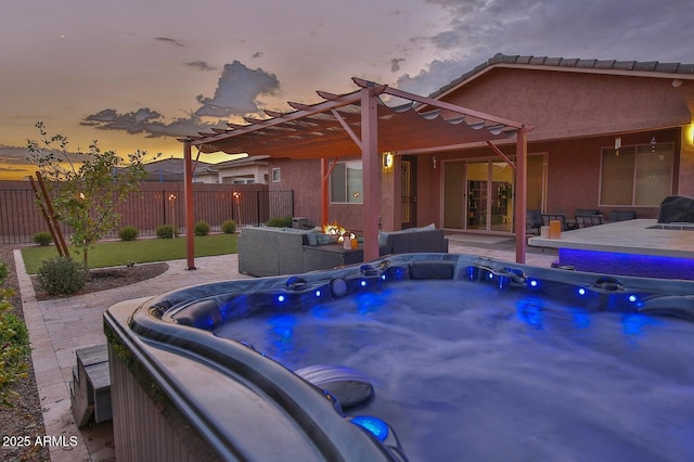 patio terrace at dusk with fence, a pergola, and a hot tub