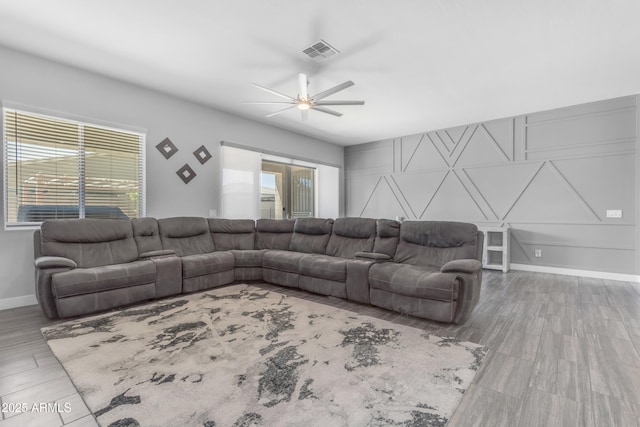 living area with visible vents, a ceiling fan, and baseboards