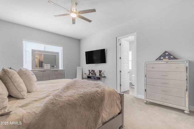 bedroom with light colored carpet, ceiling fan, ensuite bath, and baseboards
