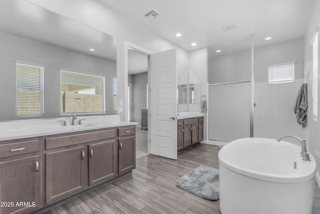 full bathroom featuring visible vents, recessed lighting, vanity, and a freestanding bath