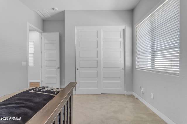 bedroom with baseboards, visible vents, a closet, and light colored carpet