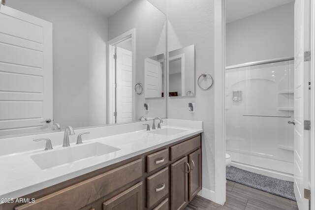 full bath featuring a sink, a shower stall, double vanity, and toilet