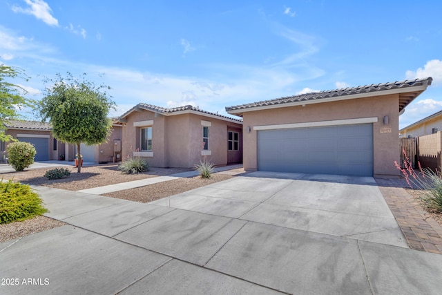 view of front of property featuring stucco siding, a tile roof, driveway, and a garage
