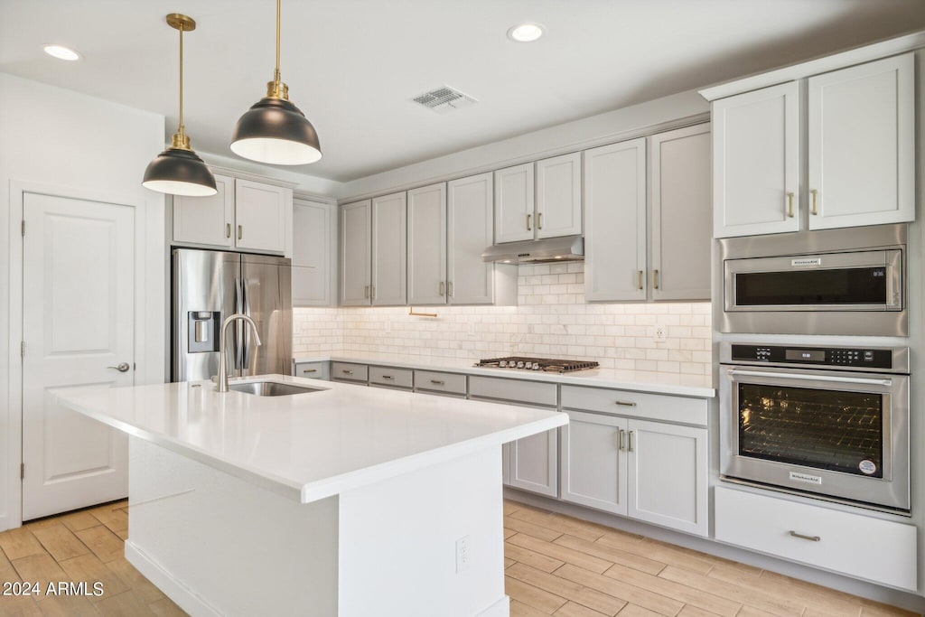 6412 N 17th Pl, Phoenix, AZ 85016 - kitchen with appliances with stainless steel finishes, light wood-type flooring, under cabinet range hood, a sink, and light countertops