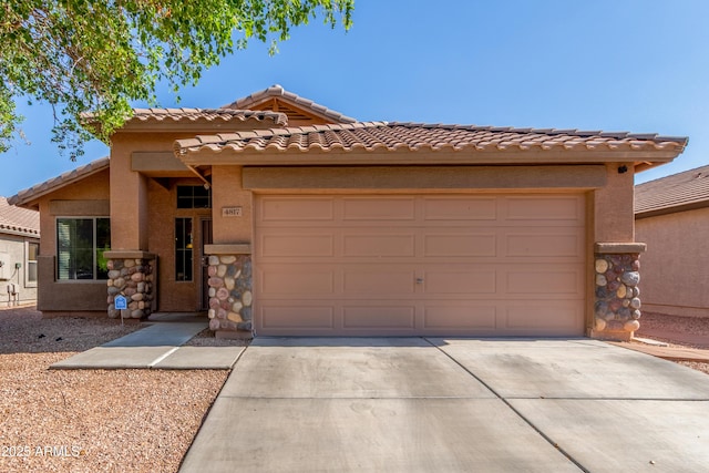 4817 W St Charles Ave, Laveen, AZ 85339 - view of front of property featuring driveway, an attached garage, a tile roof, stone siding, and stucco siding