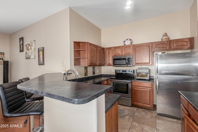 4817 W St Charles Ave, Laveen, AZ 85339 - kitchen with stainless steel appliances, dark countertops, a peninsula, a breakfast bar area, and open shelves