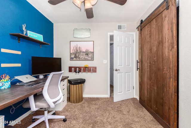 carpeted office featuring ceiling fan and a barn door