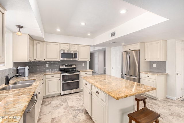 kitchen with appliances with stainless steel finishes, decorative backsplash, sink, a center island, and a breakfast bar