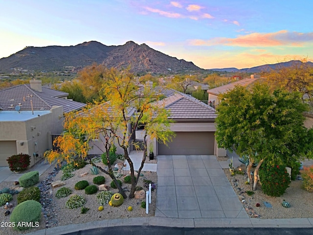 view of front of property with a garage, stucco siding, a tiled roof, and a mountain view