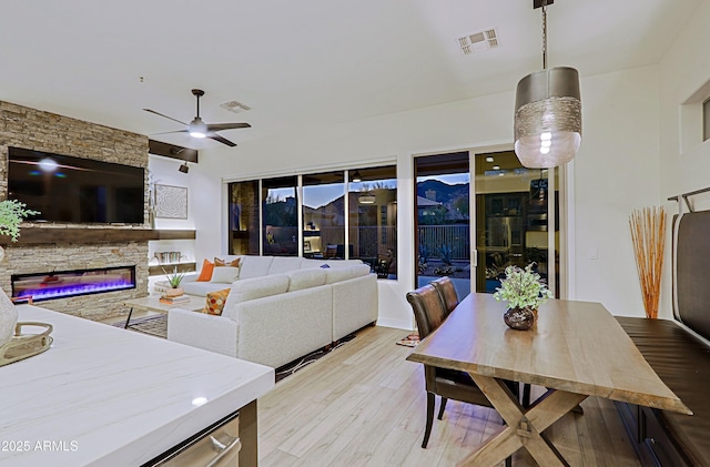 living room with visible vents, ceiling fan, light wood finished floors, and a fireplace