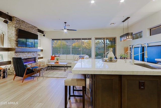 kitchen with a sink, open floor plan, light countertops, light wood-style floors, and dark brown cabinets