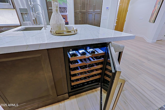kitchen with stainless steel refrigerator with ice dispenser, light stone countertops, built in microwave, wine cooler, and a sink