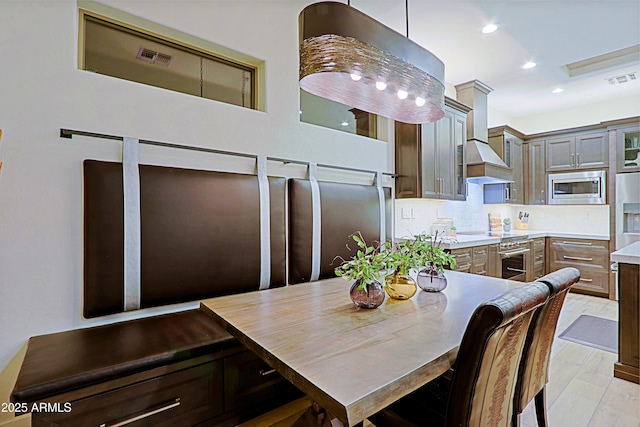 dining area with light wood-style floors, visible vents, and recessed lighting