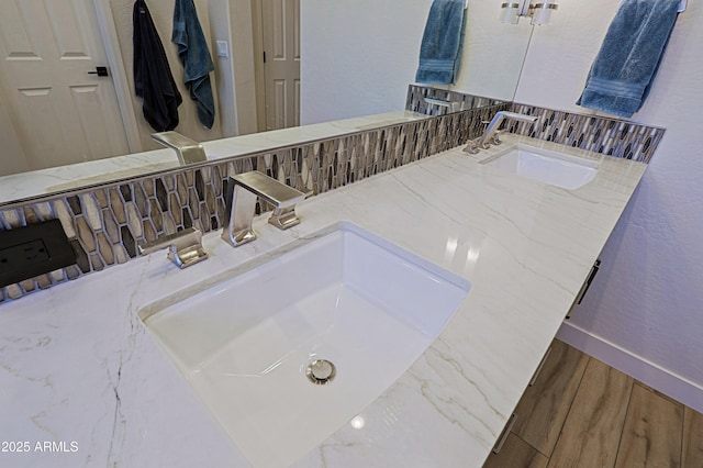 bathroom featuring a sink, decorative backsplash, wood finished floors, and a textured wall