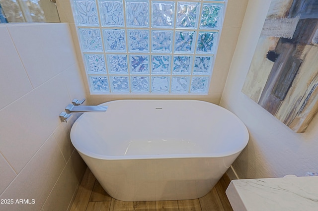 full bathroom with tile walls and a freestanding tub