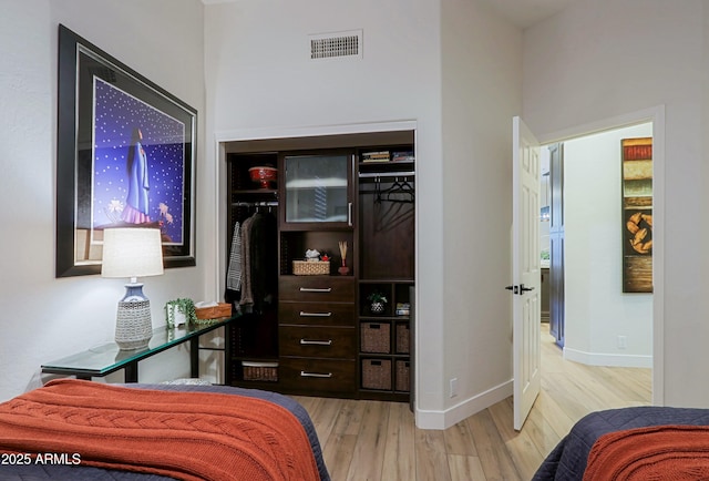 bedroom featuring visible vents, baseboards, a closet, and wood finished floors