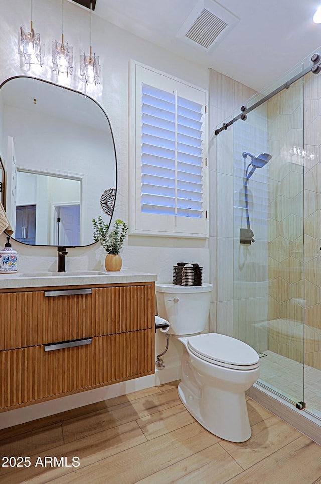 bathroom featuring visible vents, toilet, a stall shower, and wood finished floors