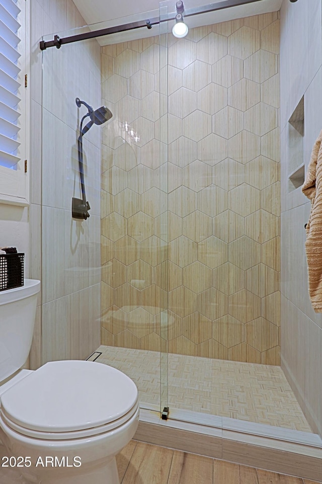 full bathroom featuring tiled shower and toilet