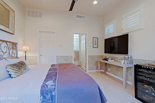 bedroom featuring light tile patterned floors, visible vents, a wainscoted wall, and wine cooler