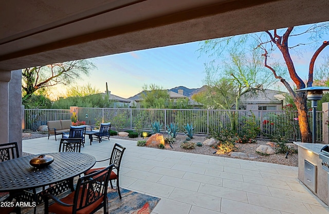 patio terrace at dusk with outdoor dining area and a fenced backyard