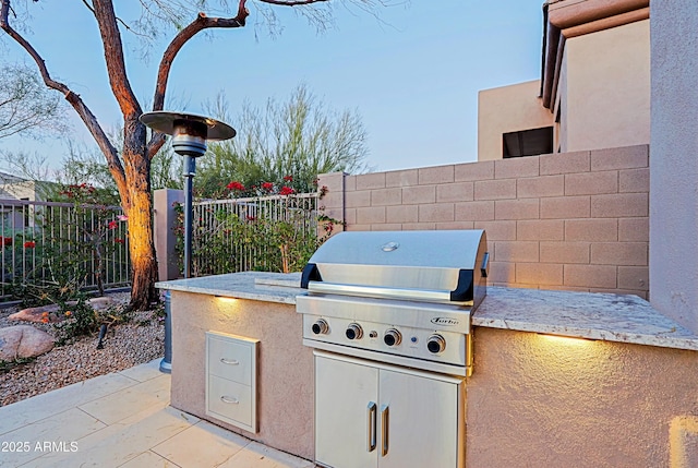 view of patio featuring grilling area, fence, and exterior kitchen
