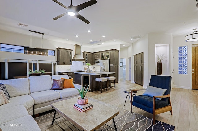 living room featuring visible vents, baseboards, ceiling fan, light wood-style floors, and recessed lighting
