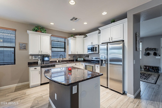 kitchen with white cabinetry, sink, light hardwood / wood-style floors, a kitchen island, and appliances with stainless steel finishes