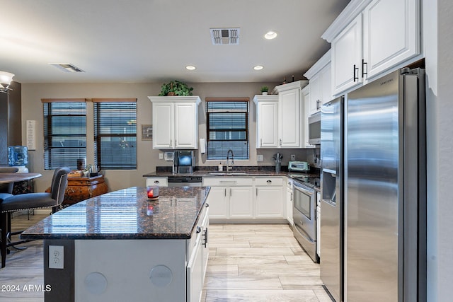 kitchen featuring white cabinetry, sink, dark stone counters, and appliances with stainless steel finishes