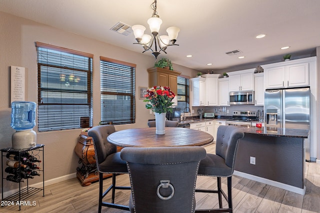 dining area featuring an inviting chandelier, light hardwood / wood-style flooring, and sink