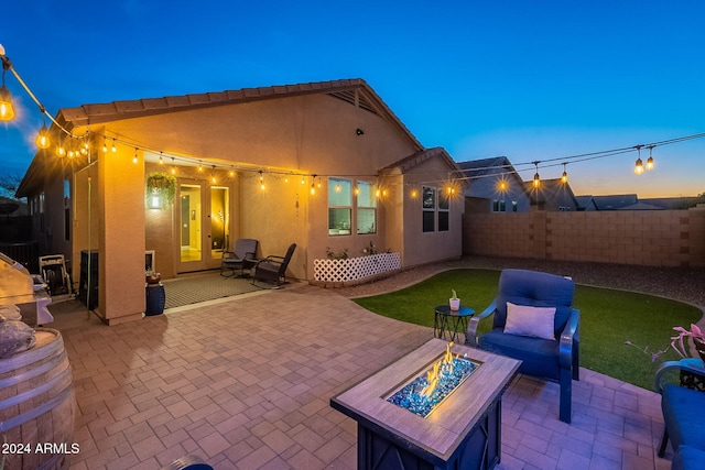 back house at dusk featuring a fire pit and a patio area